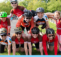 An image of NBTS riders at a biking endurance event, kneeling on top of one another in a pyramid.