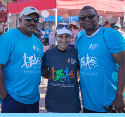 Image of three participants smiling besides a registration tent at the Orange County Brain Tumor Walk.