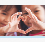 Image. Two little girls place their hands together in the shape of a heart.