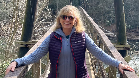 Amy, an ependymoma survivor, stands smiling on a bridge.