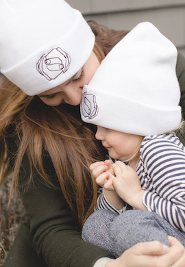 An adult and child in matching My Hand in Yours beanies.