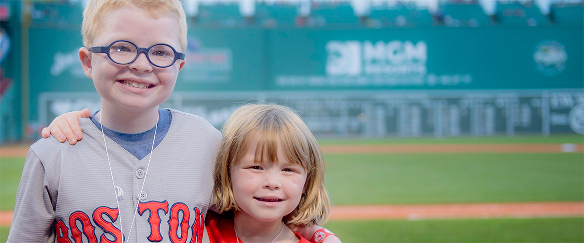 A young Dana-Farber Jimmy Fund Clinic patient and his sister on the field at Fenway Park