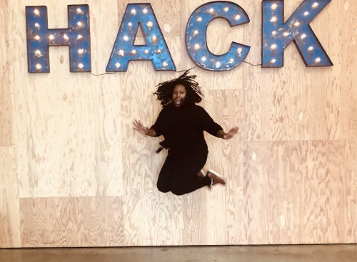 ESIA Alumna Brooke Pearson jumping in front of Hack sign
